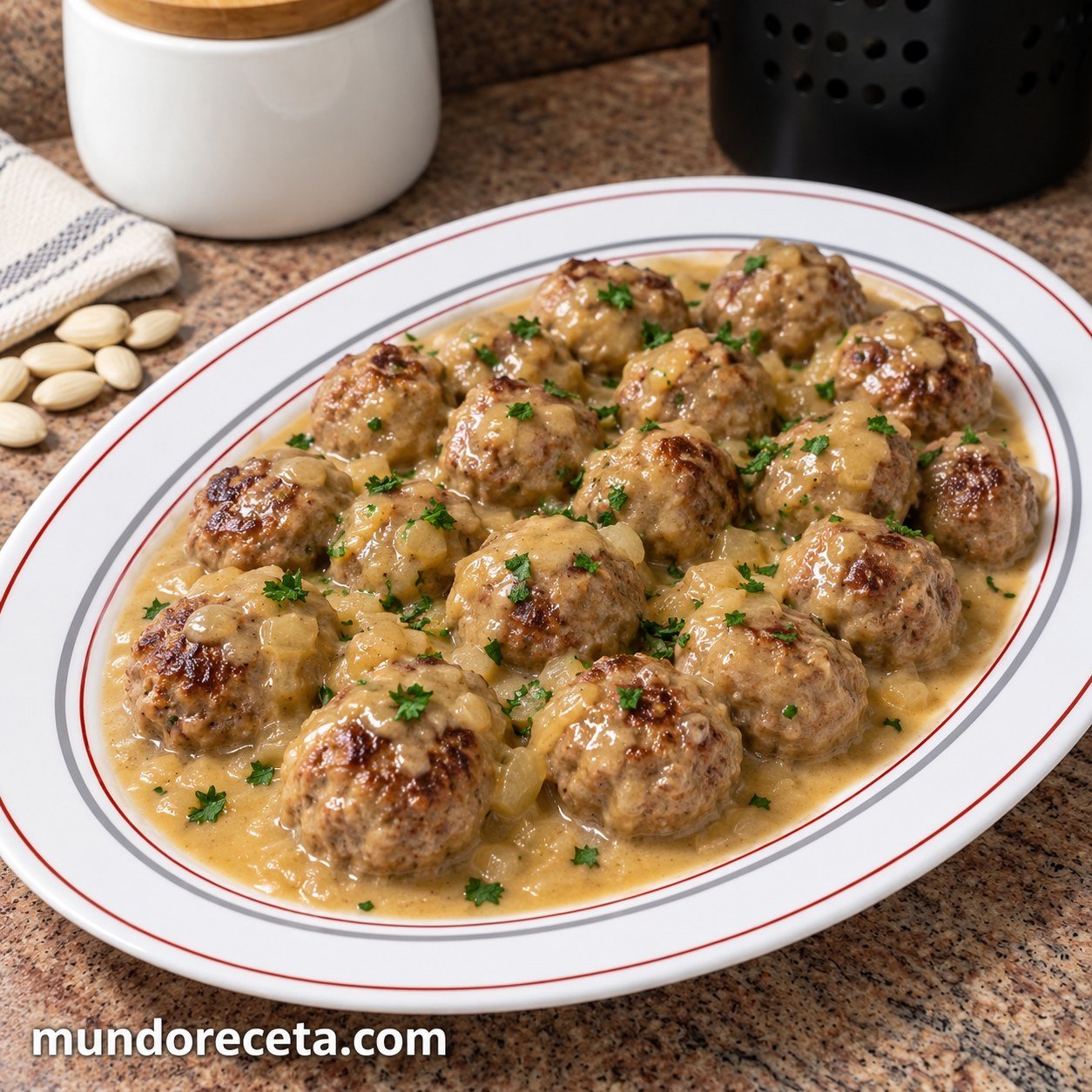 Albóndigas caseras en salsa de almendras sobre una bandeja blanca con ribetes rojos y grises